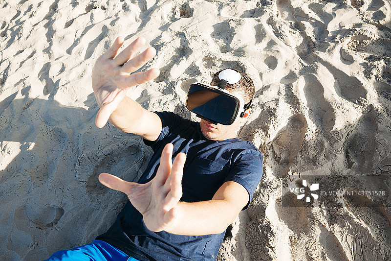 男子佩戴VR眼镜躺在沙滩上图片素材