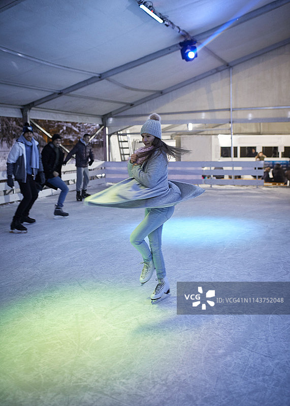 年轻女人在夜间溜冰场上旋转，朋友们在观看图片素材