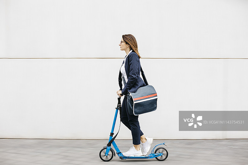 在城市里骑滑板车的活跃女商人图片素材