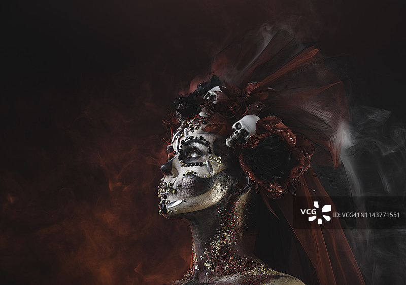 画着万圣节艺术妆容和骷髅的年轻圣死神女孩图片素材