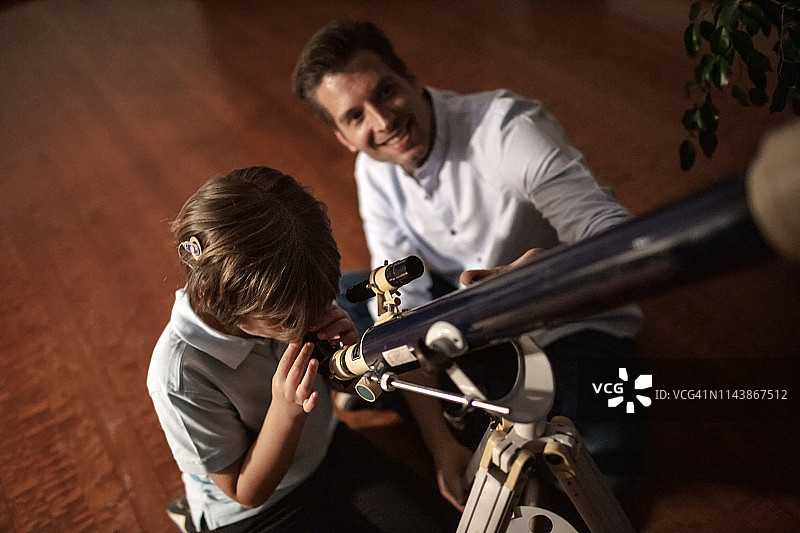 父亲和可爱的儿子用望远镜看天空图片素材