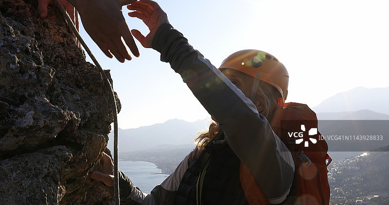 攀岩者在海边悬崖上伸手图片素材