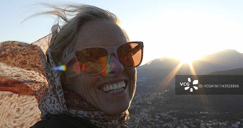 中年妇女在山区刮风的天气里欣赏日出图片素材