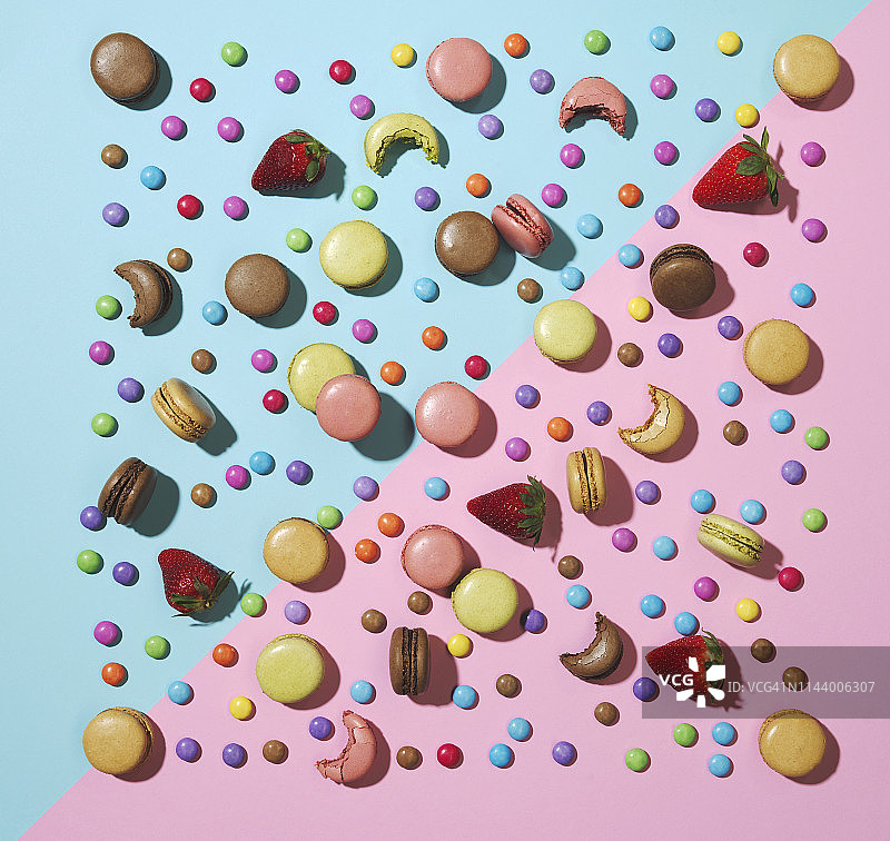 粉色背景上的稀疏糖果、草莓和马卡龙图片素材