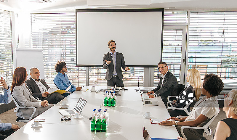 在办公室做演示时与同事交谈的年轻经理图片素材