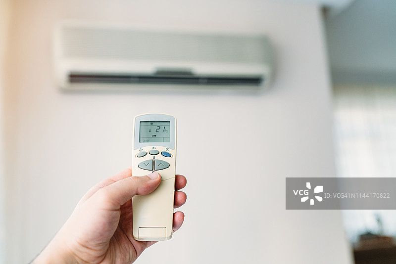手持遥控器操作空调特写图片素材
