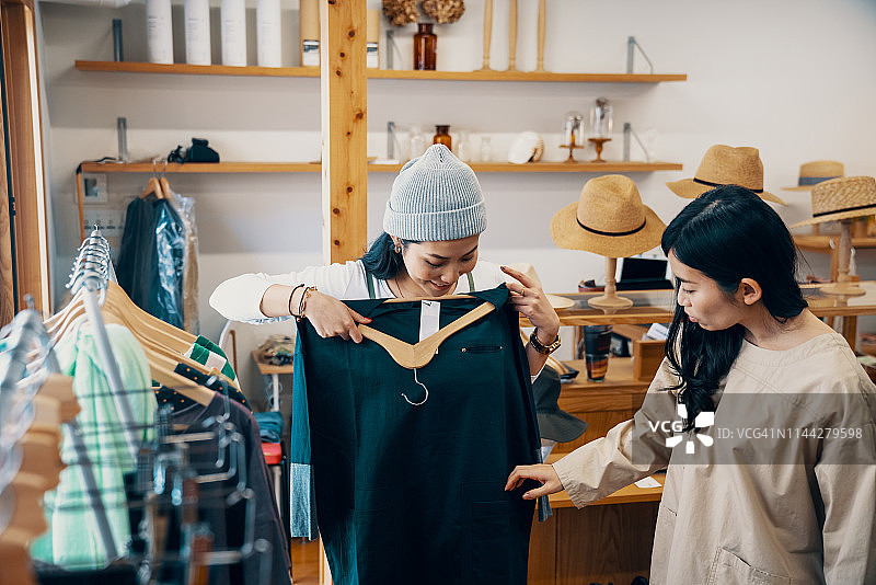 零售店员帮助中年女性顾客在精品店选购服装图片素材