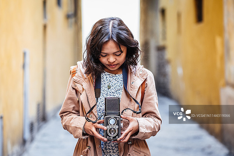 年轻女摄影师在城市里拿着老式相机图片素材