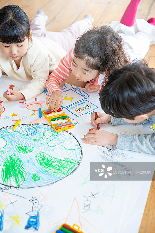 儿童用蜡笔在纸上绘画图片素材