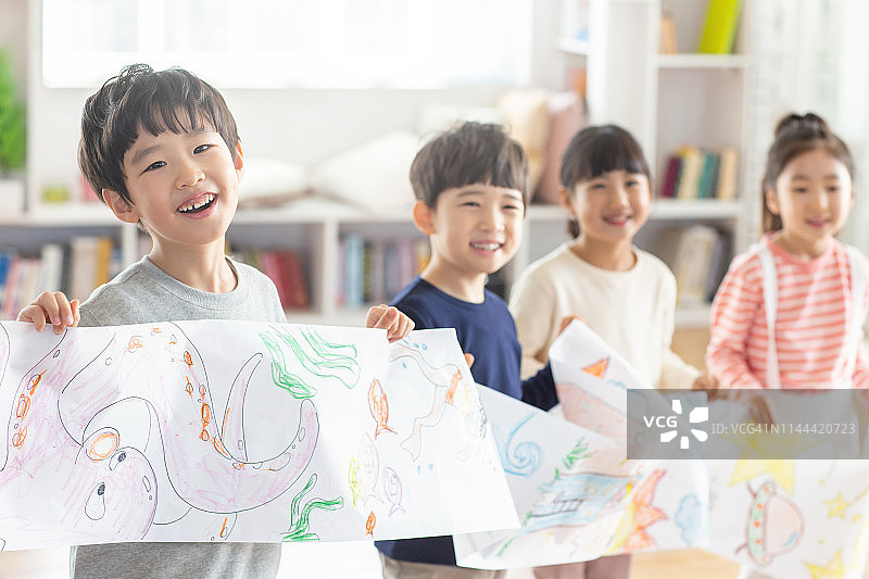 微笑的儿童拿着图画纸图片素材