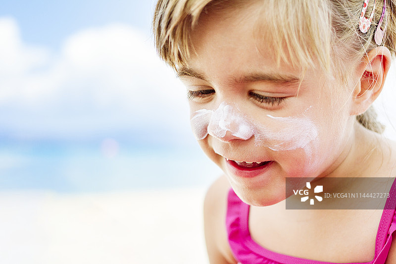 可爱女孩脸上涂防晒霜图片素材