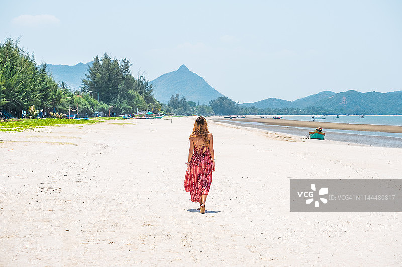 夏日假期红裙美丽女人沙滩漫步图片素材