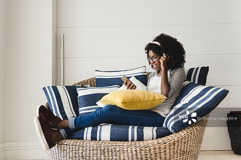 在客厅沙发上用手机听音乐休息的少女图片素材