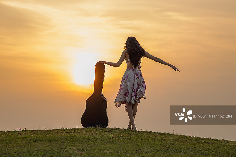 穿着鲜艳的女人在日落时享受音乐图片素材