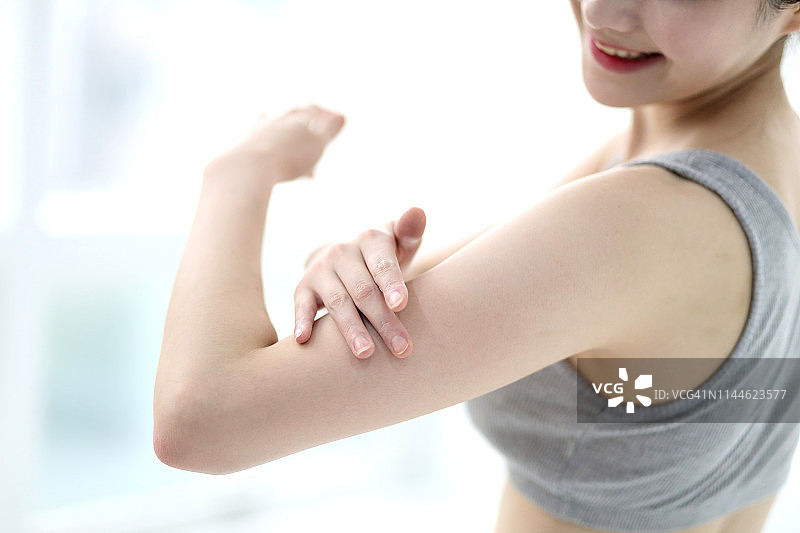 女人在手臂上涂抹润肤露图片素材