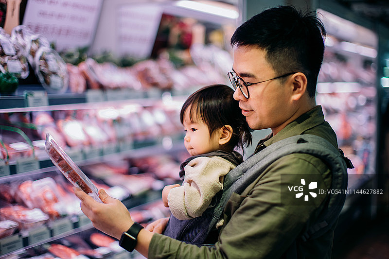 年轻的亚洲父亲和可爱的女儿在超市购买新鲜家禽图片素材