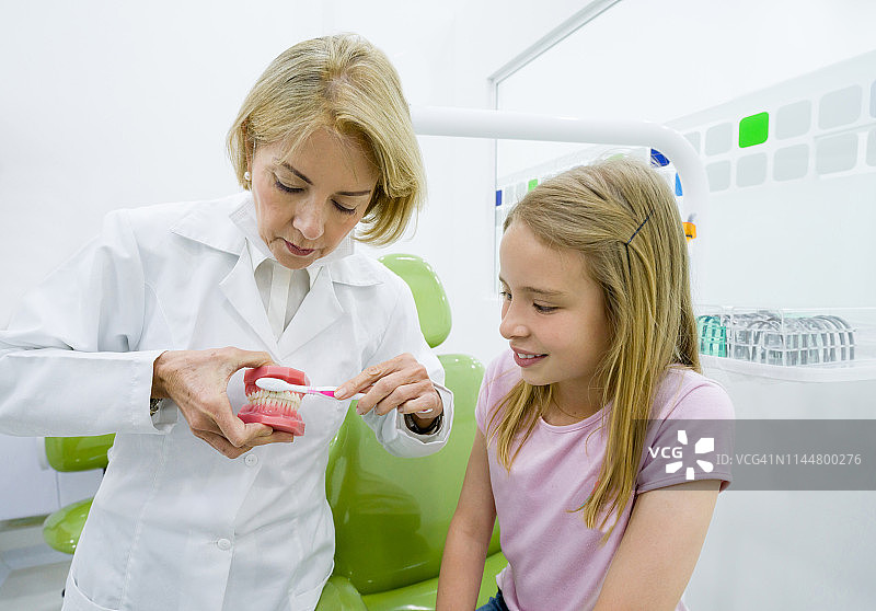 牙科医生示范女孩如何刷牙图片素材