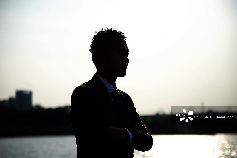 在日落时分双手抱胸的商人图片素材