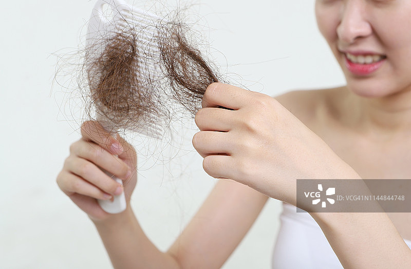 女人拿着带有掉落头发的梳子图片素材