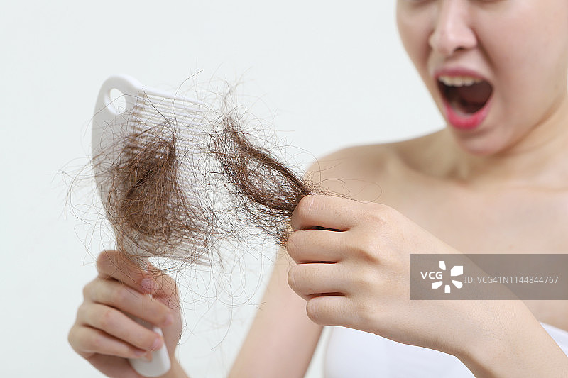 惊讶的女人拿着掉发的梳子图片素材