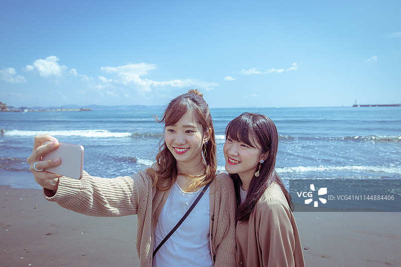 年轻女性朋友在海滩上自拍图片素材