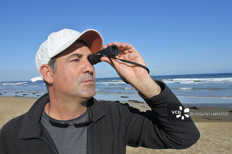 用单筒望远镜观察的成年男人图片素材