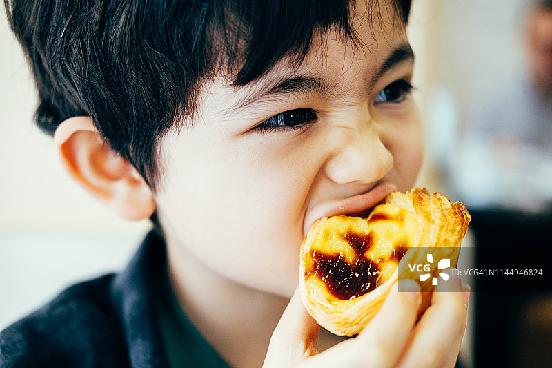 男孩在吃葡式蛋挞图片素材