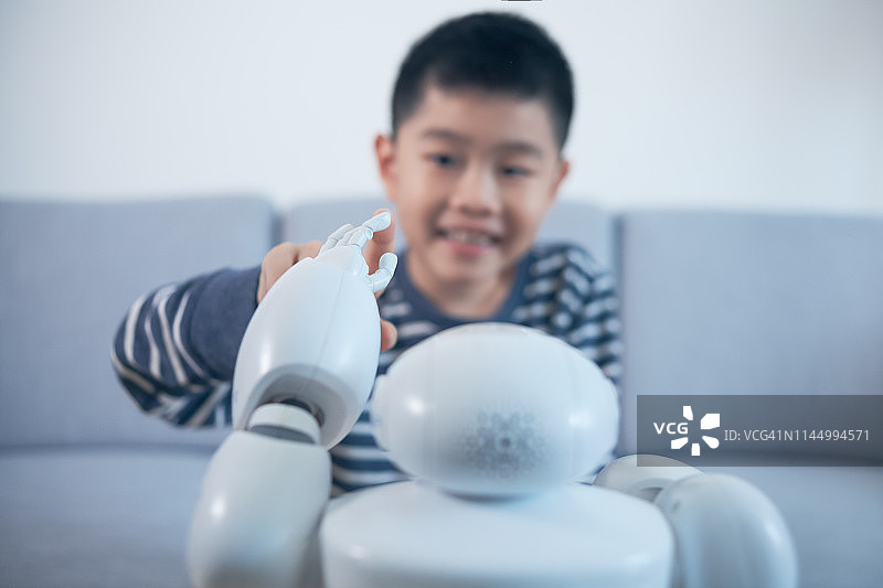 聪明的男孩在室内触摸机器人手指图片素材