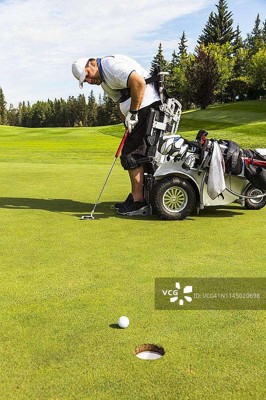 一位肢体残疾的高尔夫球手使用专用电动液压轮椅在高尔夫球场上推球图片素材
