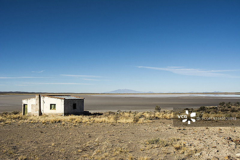 干涸湖床与远山火山，前景废弃白楼图片素材