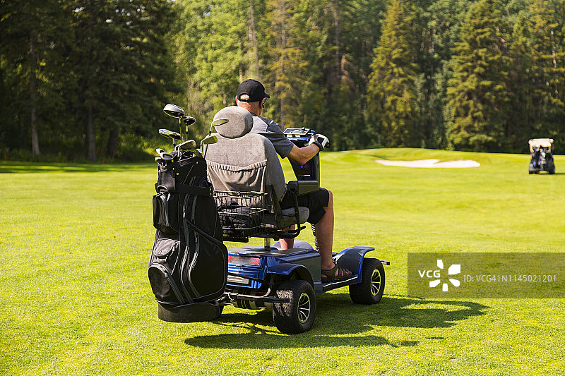 残疾人高尔夫球手在比赛期间驾驶专用高尔夫轮椅穿梭于球洞之间图片素材