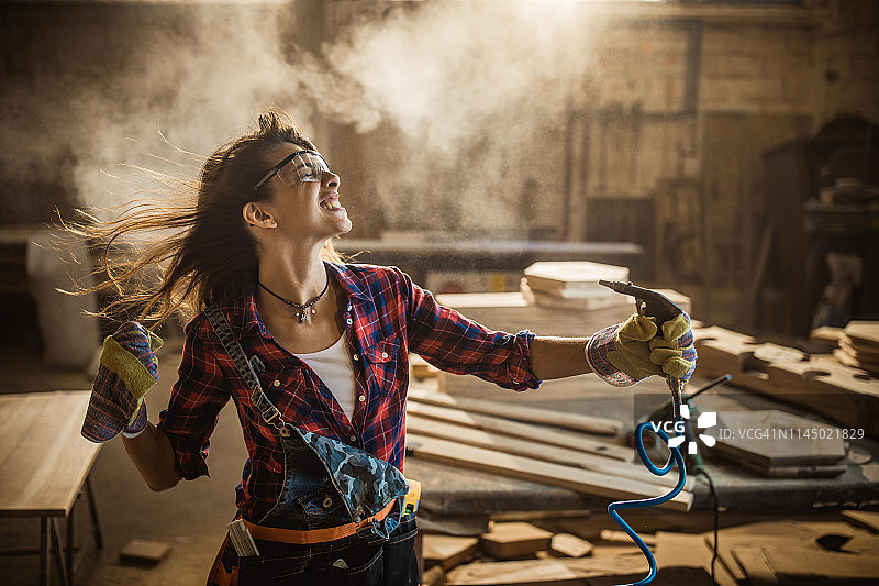在车间里用气枪玩耍的女工图片素材