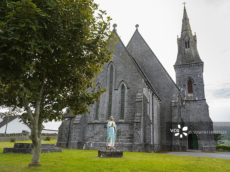 带钟楼的石砌教堂和祈祷妇女雕像图片素材