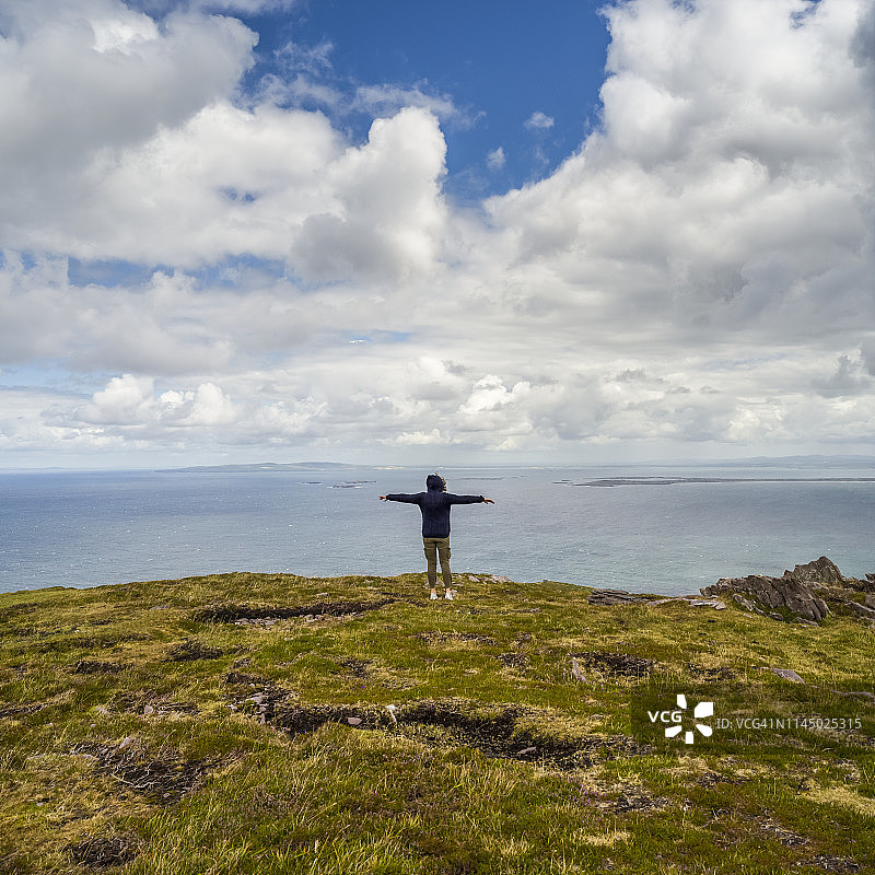 在丁格尔半岛布兰登角，女子伸出双臂，眺望大海和海岸线图片素材