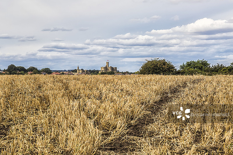 稻草田野中的V形轨迹，框住明媚夏日傍晚的沃克沃思城堡图片素材