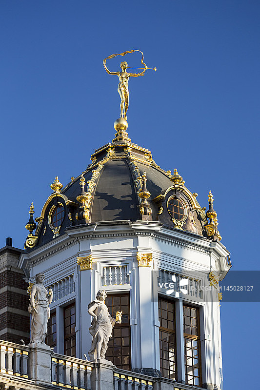 带有金色装饰和金色雕像的圆顶塔楼建筑特写，背景是蓝天图片素材