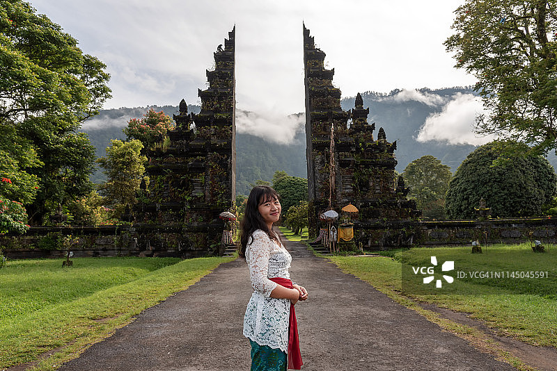 巴厘岛典型大门前的巴厘岛年轻女人图片素材