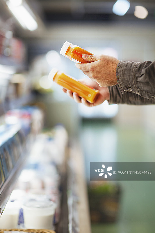 在超市里，双手拿着果汁瓶图片素材