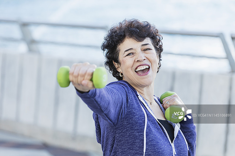 用手持重物锻炼的年长的西班牙裔女人图片素材