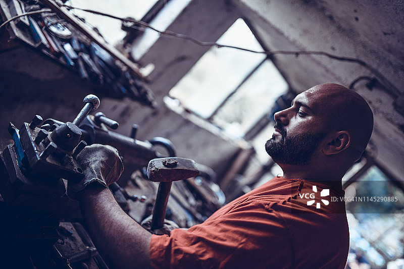 用锤子敲击并矫正零件的维修工图片素材