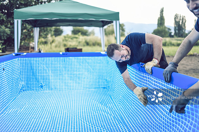 确保游泳池各处光滑的微笑工人们图片素材