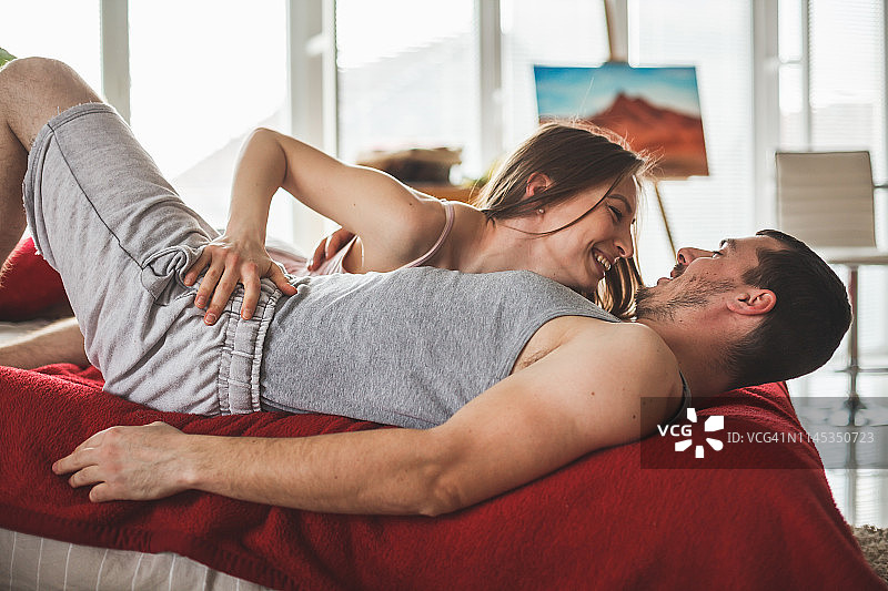 微笑的年轻情侣在床上图片素材