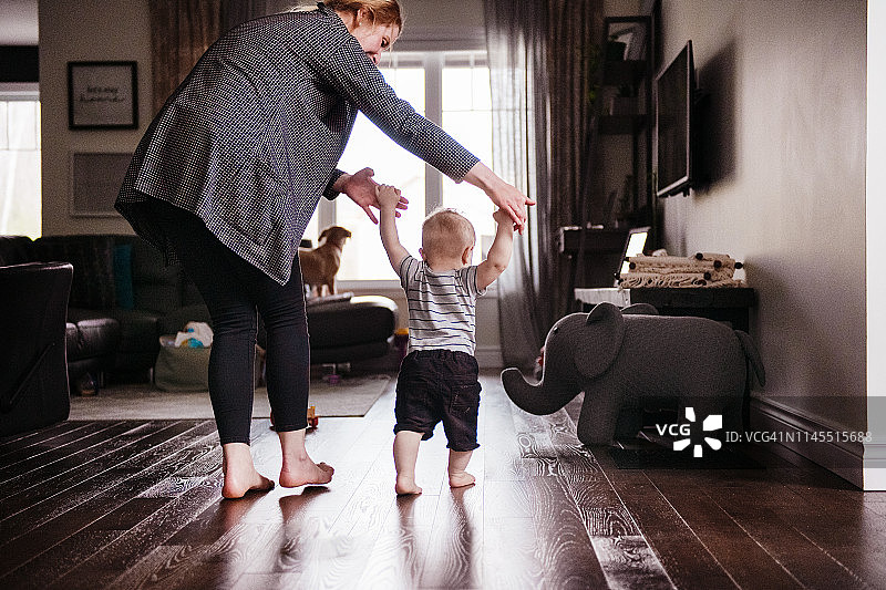 父母在家观看并帮助宝宝儿子迈出第一步图片素材
