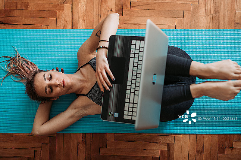 在家做瑜伽和使用笔记本电脑的女人图片素材