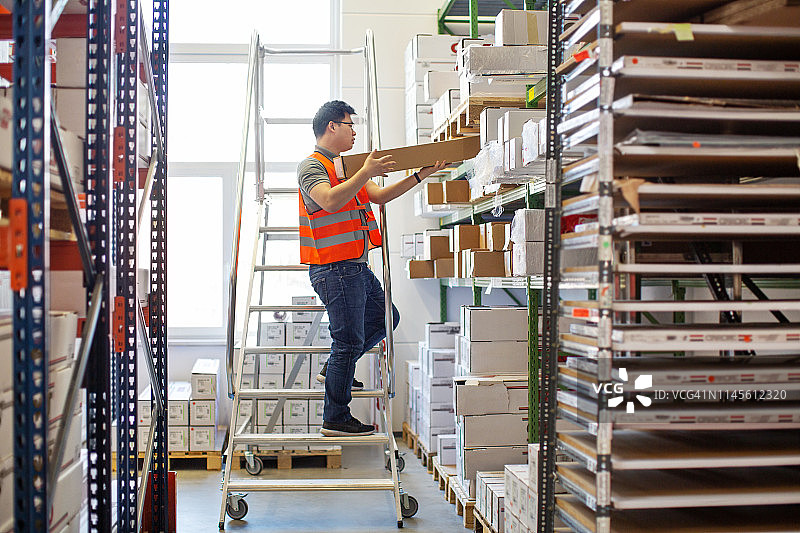 工人在仓库中把箱子放到架子上图片素材