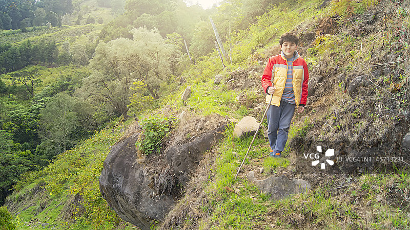 拿着登山杖站在山丘上的男孩图片素材