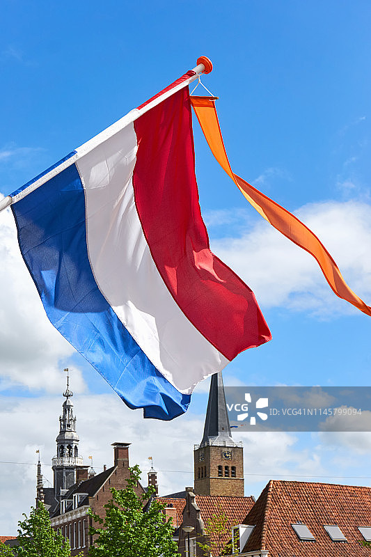 国王节期间在风中飘扬的带有橙色彩带的荷兰国旗图片素材