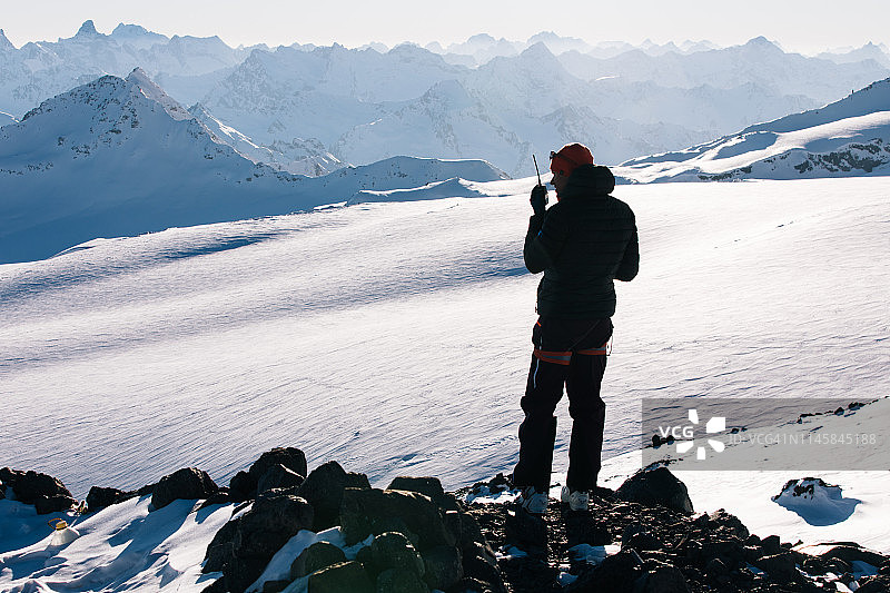 登山者在黄昏时于山顶使用对讲机图片素材