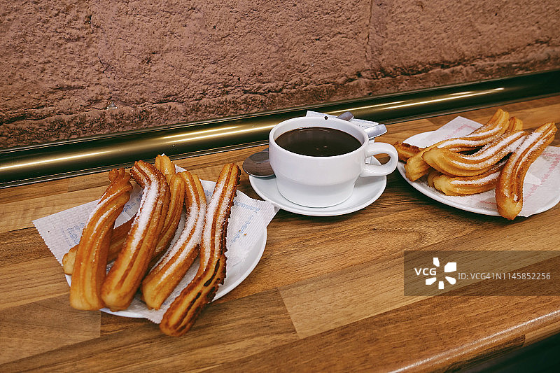 西班牙油条和热巧克力在木桌上特写图片素材