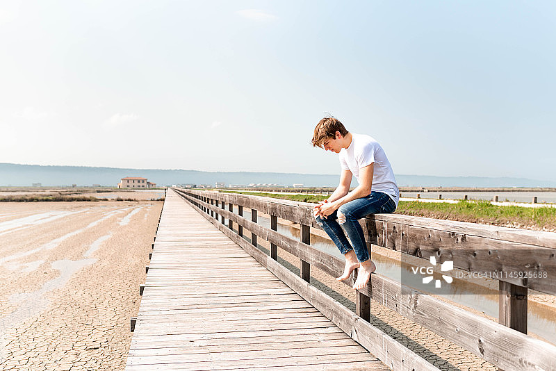 年轻人坐在木栅栏上图片素材
